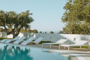 法萨诺马塞里亚博尔戈里特拉酒店的游泳池旁的一排白色躺椅