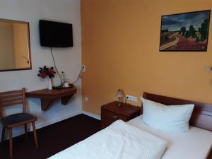 比尔弗登Hotel Gasthof Zur Krone的酒店客房配有一张床、一把椅子和一台电视。