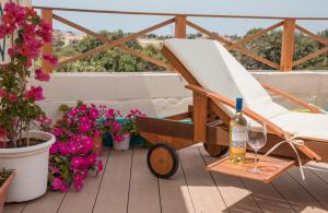 KirkopTal-Karmnu Entire house with private heated pool and jacuzzi的鲜花阳台的椅子和一瓶葡萄酒