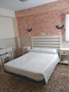 滨海罗克塔斯佩德罗胡安膳食公寓酒店的卧室配有一张白色的床和大型床头板