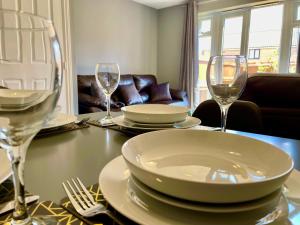 诺里奇Queens Lodge - Beautiful Modern House with Free Parking - Marvello Properties的一张桌子上放有盘子和酒杯