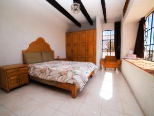 塔斯科·德·阿拉尔孔Casa de las Cruces Taxco的一间卧室配有一张床、一把椅子和窗户。