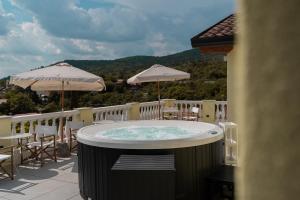 西斯蒂亚纳Locanda Gaudemus Boutique Hotel的阳台上的热水浴池配有桌子和遮阳伞