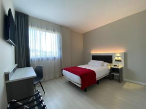 德里奥新毕尔巴鄂机场酒店的酒店客房,配有一张带红色毯子的床