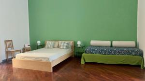 那不勒斯卡萨戴尔皮利比赛奇图公寓的配有绿色墙壁和木地板的客房内的两张床