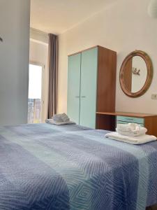 里米尼布鲁门酒店的一间卧室配有一张带镜子的蓝色床