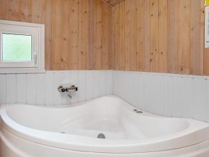 耶鲁普6 person holiday home in Jerup的浴室设有白色浴缸,拥有木墙