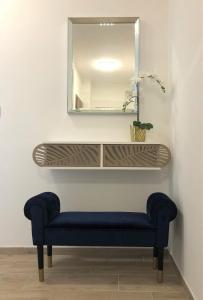 陶波尔曹Glamour Apartman的一个带蓝色长椅和镜子的架子