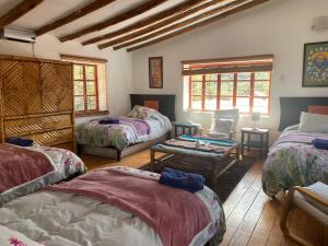 库斯科Casa de la Gringa Mountain House的带三张床和一张桌子的房间