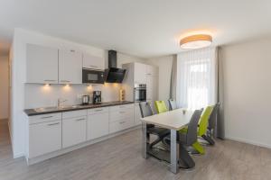 IftaWohlfühlappartements „Natur & Flair“的厨房配有白色橱柜和桌椅