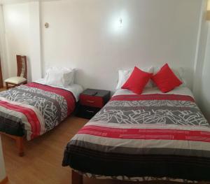 阿雷基帕La Casa de Leonardo YANAHUARA的一间卧室配有两张带红色枕头的床