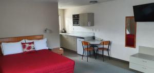 阿什伯顿阿什伯顿丽晶汽车旅馆的一间带红色床的卧室和一间小厨房