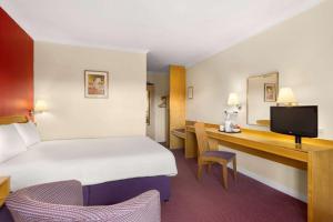 汉密尔顿汉密尔顿戴斯酒店的酒店客房设有一张大床和一张书桌。