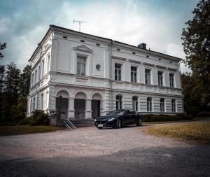 SvartåMustion Linna / Svartå Manor的停在白色建筑前面的汽车