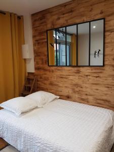 ÉpoyeL'Hébergerie的卧室配有一张壁挂镜子的床