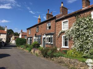 TealbyCosy Lincs Wolds cottage in picturesque Tealby的街上的砖房,有白色的窗户