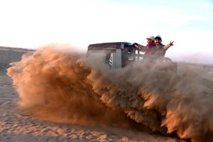 斋沙默尔Exotic Luxury Camps的两个人乘坐沙漠里的吉普车