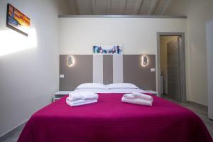 帕尔马Le PALME的一间卧室配有粉红色的床和2条毛巾