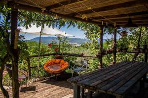 维基奥Tuscan hills near Florence - stone house的木制甲板配有桌子、椅子和遮阳伞