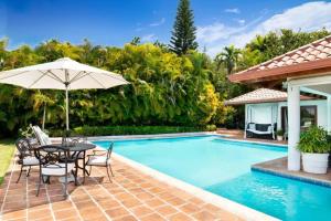 拉罗马纳Los Lagos 19- Golf and Lake View 5-Bedroom Villa的游泳池旁带桌子和遮阳伞的天井