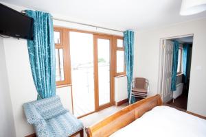 邓坎嫩Fort Conan Hotel的卧室配有床、椅子和窗户。