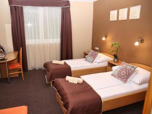 米什科尔茨道波曹ALFA Hotel & Wellness Miskolctapolca的酒店客房设有三张床和一张桌子