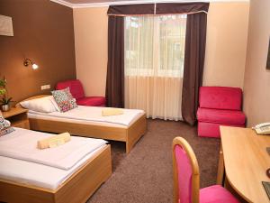 米什科尔茨道波曹ALFA Hotel & Wellness Miskolctapolca的一间设有两张床和一张桌子及椅子的房间