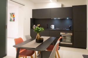 阿奇卡斯泰洛Mori Siciliani House的黑色的厨房,配有桌子和一些橙色椅子