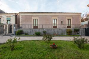 阿奇卡斯泰洛Mori Siciliani House的一座大砖砌建筑,院子里有花盆