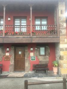 RalesLA CASONA DE RALES VILLAVICIOSA的红色的房子,设有木门和阳台