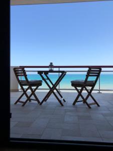 泰尔莫利SunRise Apartments的阳台配有一张桌子和两把椅子,享有海景