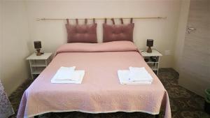 蓬扎Visitponza - La casa di Eolo的一间卧室配有粉红色的床和2条毛巾