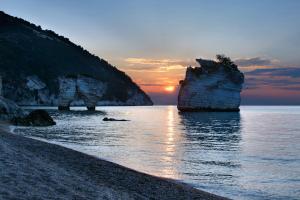 马蒂纳塔AH Premium Baia dei Faraglioni的海滩上的日落,岩石在水中