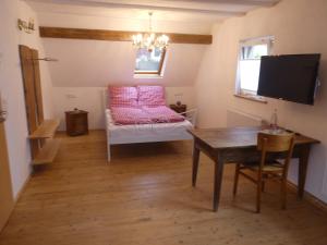 Weisweils' Moose Hof的客房配有桌子和带粉红色枕头的床。