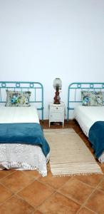雷根古什-迪蒙萨拉什Casa do Avô Tó的一间卧室配有两张床和一张带台灯的桌子
