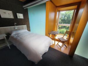 戈特赫斯阿特亚加Urdaibai Bird Center的一间卧室设有一张床、一个窗口和一把椅子