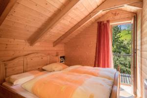 TannenHaus der Sinne Bregenzerwald的木制客房的一张床位,设有窗户