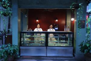 加尔各答The Elgin Fairlawn, Kolkata的两个人站在柜台后面,拿着食物