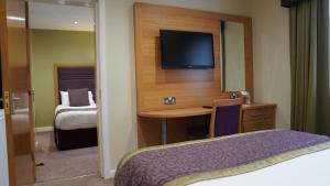 哈德斯菲尔德石楠府酒店的酒店客房配有一张床和一张书桌及一台电视