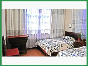 大理大理百合国际青年旅舍的一间卧室设有两张床,窗户配有窗帘