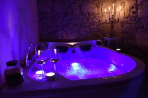 索尔索Casa Isabella Light Blue Intero Appartamento的紫色浴缸,配有酒杯和蜡烛