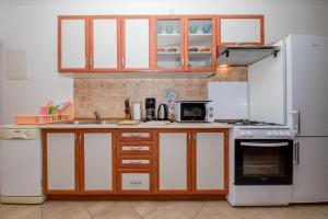 拉布Apartments Šćerbe 3103的厨房配有白色家电和木制橱柜