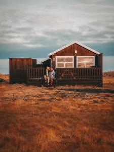 Sandgerði桑德格迪小屋酒店的一对夫妇坐在小屋前的长凳上