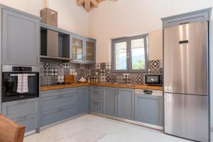 卡托克拉克阿纳Villa Dafni & Nikos Corfu的厨房配有蓝色橱柜和不锈钢冰箱