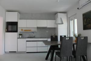帕格Apartman Boki的厨房配有白色橱柜和桌椅