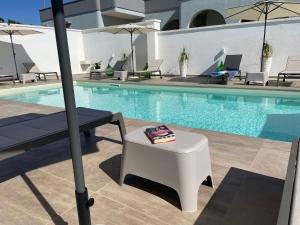 托雷苏达Elite Luxury Residence的一个带桌子、长凳和遮阳伞的游泳池