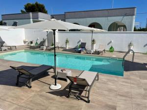 托雷苏达Elite Luxury Residence的游泳池配有桌子、遮阳伞和椅子