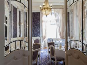 因特拉肯Hotel Royal St Georges Interlaken MGallery Collection的一间带桌椅和吊灯的用餐室