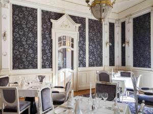 因特拉肯Hotel Royal St Georges Interlaken MGallery Collection的一间带桌椅和吊灯的用餐室