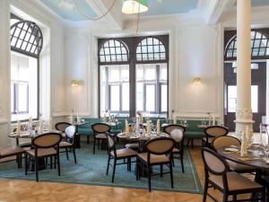 因特拉肯Hotel Royal St Georges Interlaken MGallery Collection的用餐室设有桌椅和窗户。